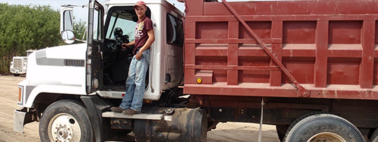 Resignola Construction dump truck on a job site with an operator standing in the open cab door