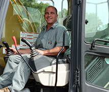 Smiling Resignola Construction operator seated at the controls of an excavator