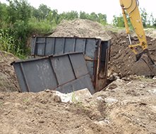 Track hoe setting a steel structure into an excavated trench